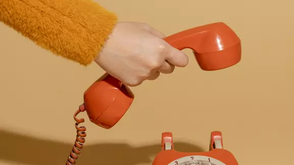 oude oranje telefoon, hand heeft de hoorn vast