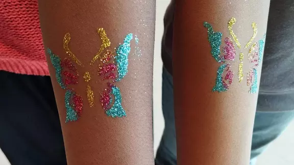 2 kinderen hebben dezelfde vlinder met geel, roze en blauw op hun arm