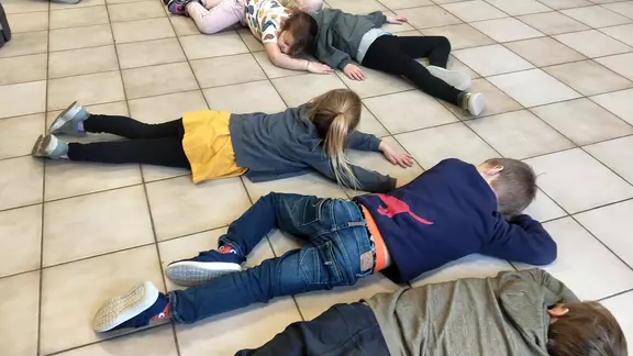 kinderen liggen op de grond en doen alsof ze slapen