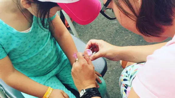 animator zet een glittertattoos op een arm