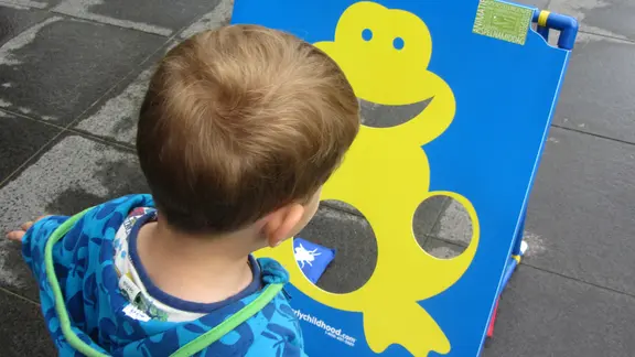 kind kijkt naar het kikkerbord om pittenzak te werpen