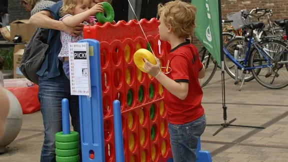 2 kinderen en een mama spelen met de reuze vier op een rij