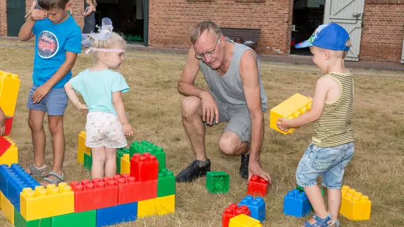 1 volwassene en 3 kinderen spelen met de bouwblokken