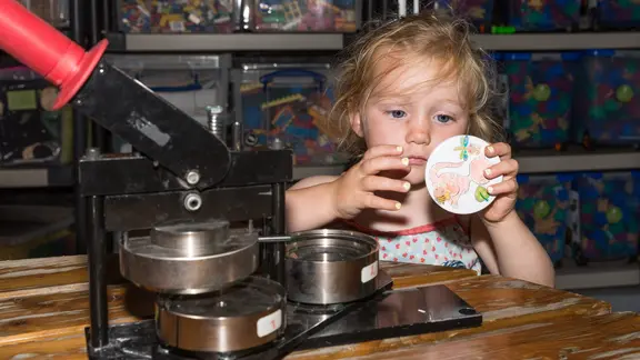 kleuter maakt een button met de machine