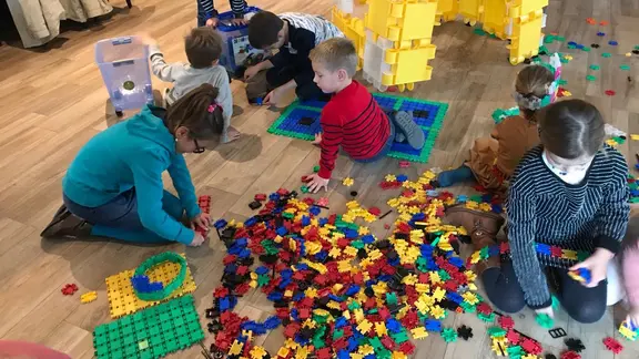 kinderen spelen met blokjes, reuzeclics bouwwerk op de achtergrond