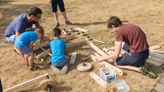 5 personen bouwen met creatool op een grasveld