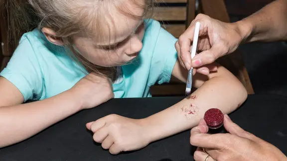 er wordt een glittertattoos gezet bij een meisje , op haar arm