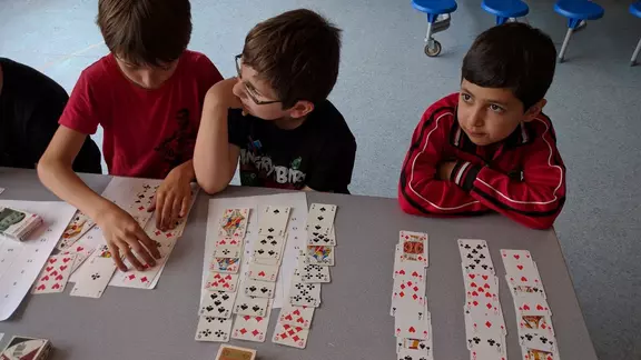 3 kinderen oefenen een truc met kaarten