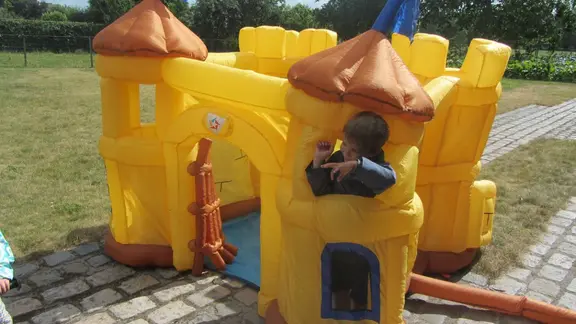 een jongetje van 5 jaar kijkt hangt door het venster van het speelkasteel