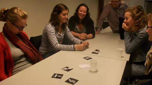 deelnemers zitten rond een tafel met kaartjes in het midden