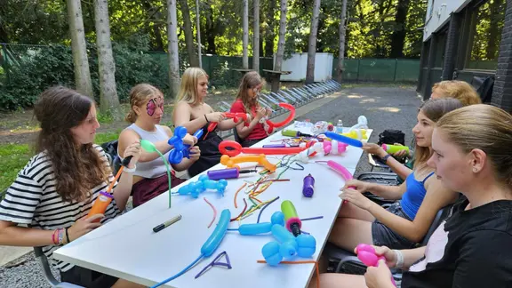 8-tal ballonplooiers rond een tafel