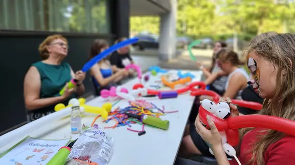 enkele ballonplooiers rond een tafel en veel ballonnen op de tafel