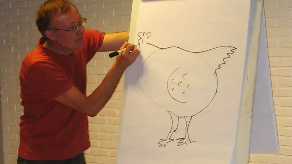 docent tekent op een groot blad een kip