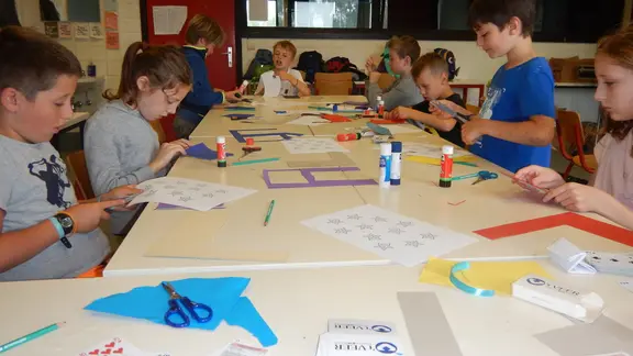 kinderen aan een tafel knutselen een goocheltruc