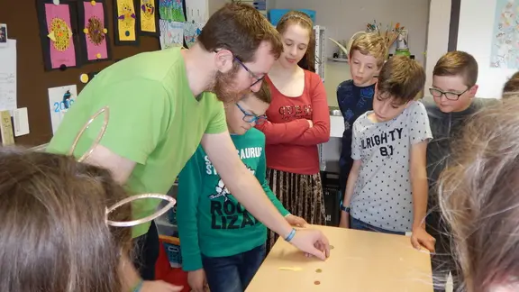 kinderen rond een tafel met goochelaar filip