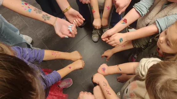 kinderen houden hun armen met glittertattoos bij elkaar