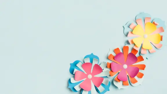 blauwe achtergrond met in de rechter onderhoek drie papieren bloemen