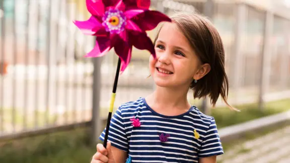een kind houdt een plastieken bloem vast die kan meedraaien met de wind