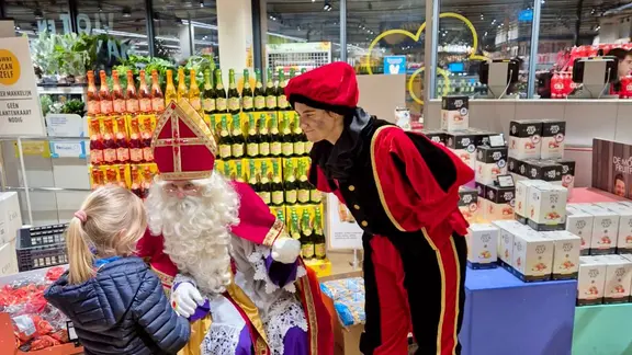 Sint en Piet spreken tegen een kindje die in een warenhuis komt winkelen