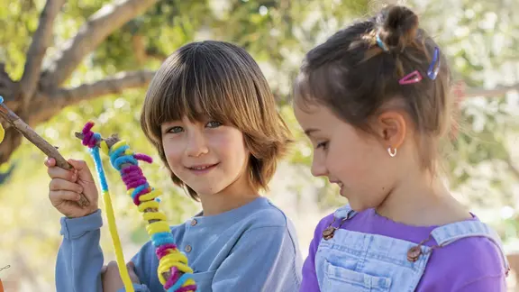 2 kinderen spelen buiten met een touw en een stok
