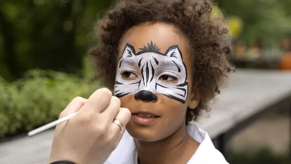 iemand schminkt een kind in een zebra