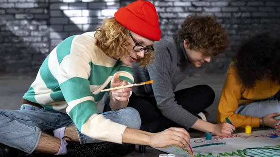 twee animatoren zijn samen aan het schilderen op karton en zitten hiervoor op de grond