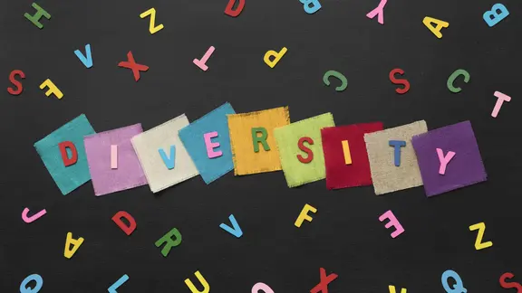 Het woord Diversity op kleurrijke blokken, met daarrond verschillende letters en een zwarte achtergrond