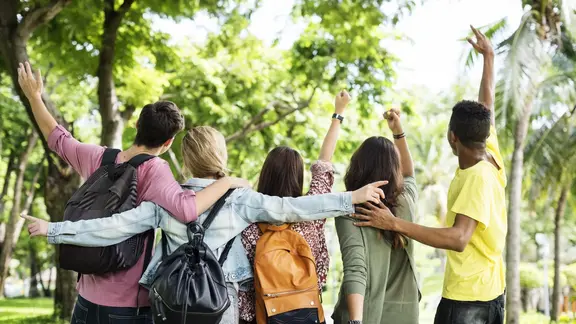 5 jongeren leggen hun armen om elkaars schouder en staan met hun rug naar de foto