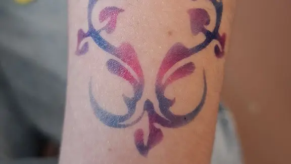 airbrushtattoo met roze en blauwe kleur ter hoogte van de pols